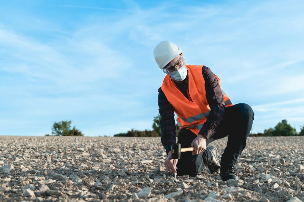 Engineer man doing topographic measures on land for construction work during coronavirus outbreak